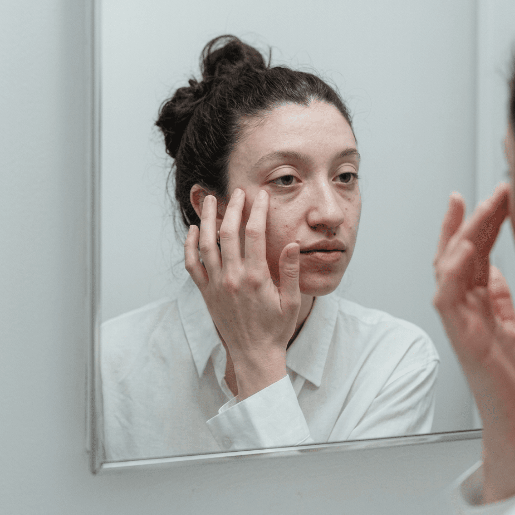 Femme qui observe son visage fatigué du matin dans le miroir
