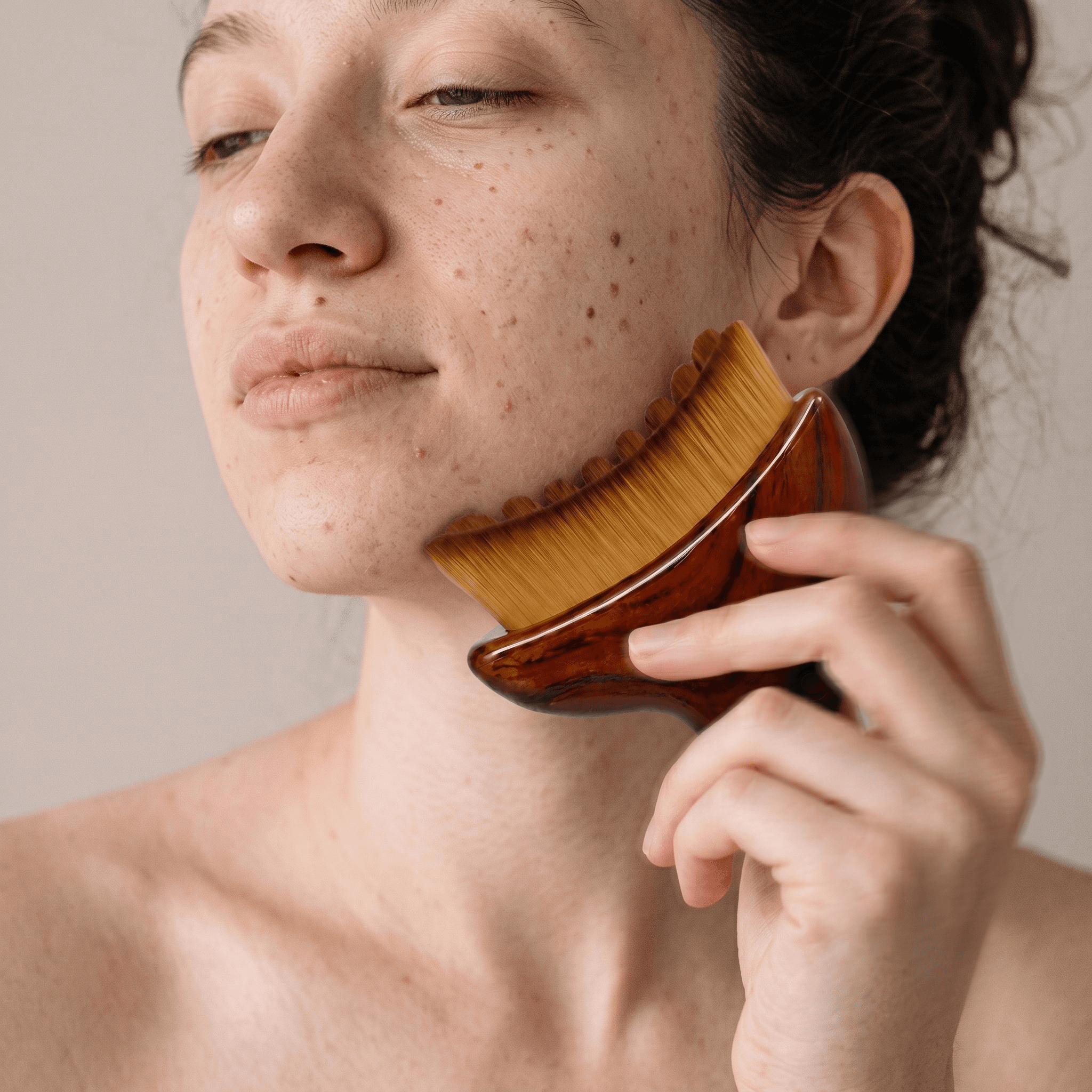 Femme utilisant la brosse Nailou (tête à poils, manche en bois) sur sa mâchoire